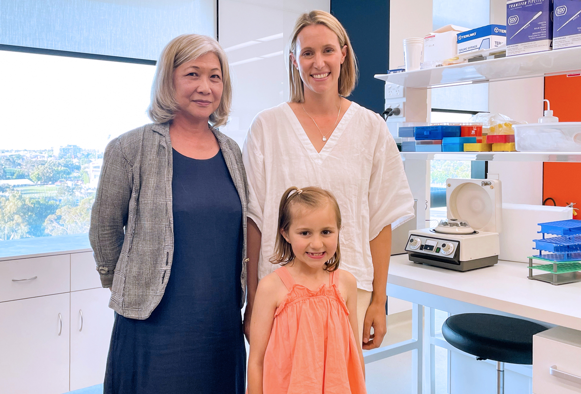 Image of Mother and child standing with medical professional in lab