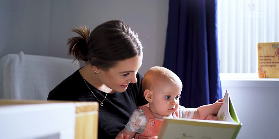 Video still of mother and baby reading a book together at home after being helped by the research foundation