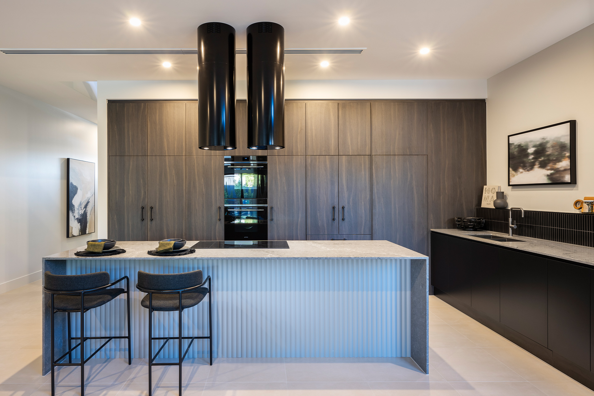 Kitchen with two feature black round exhaust tubes above the island bench