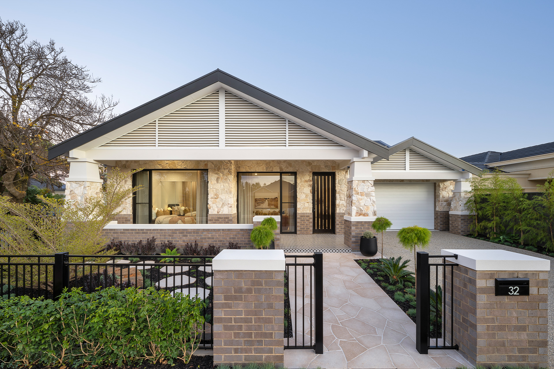 Bungalow style modern home, single story with brick and stone facade on a clear day.