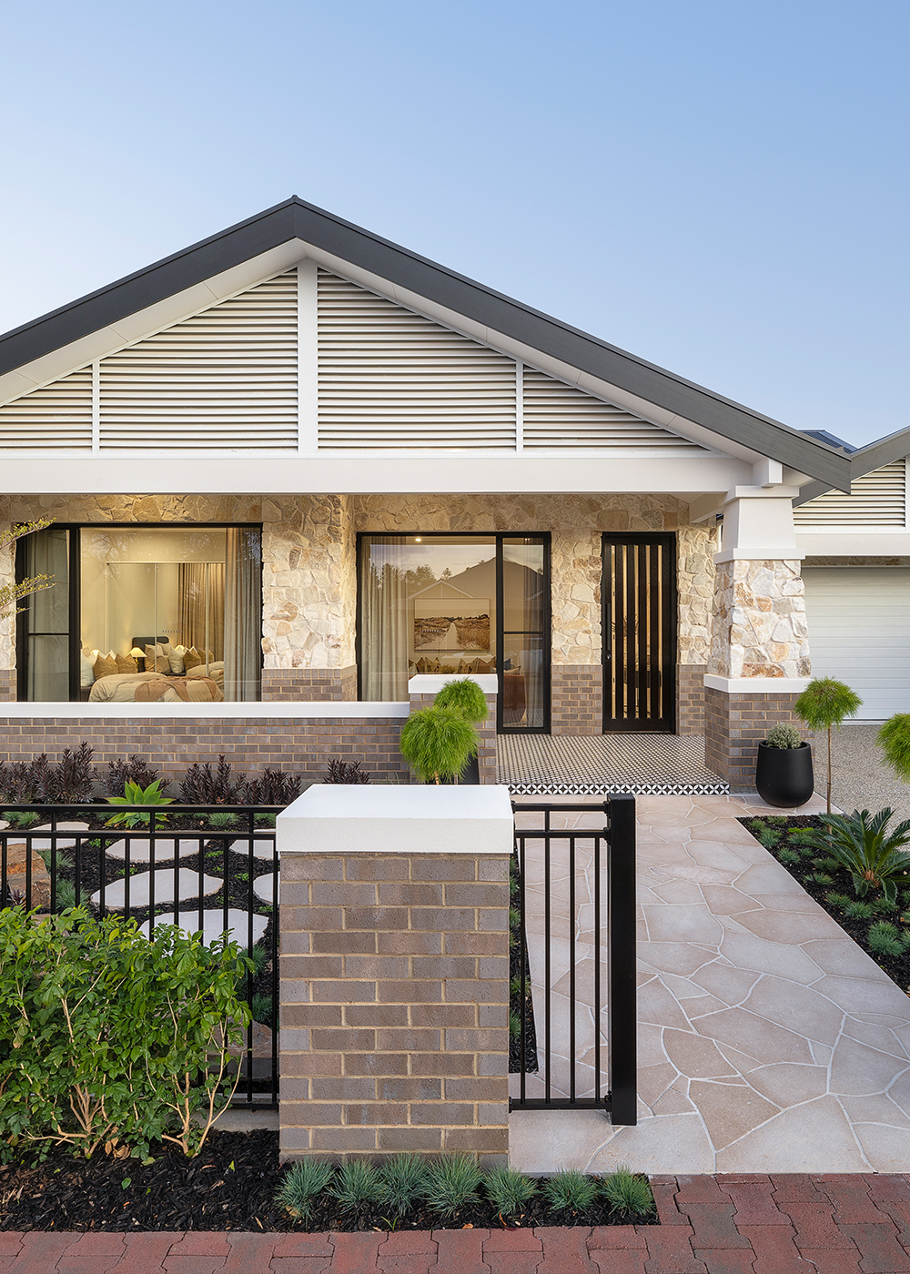Bungalow style modern home, single story with brick and stone facade on a clear day.