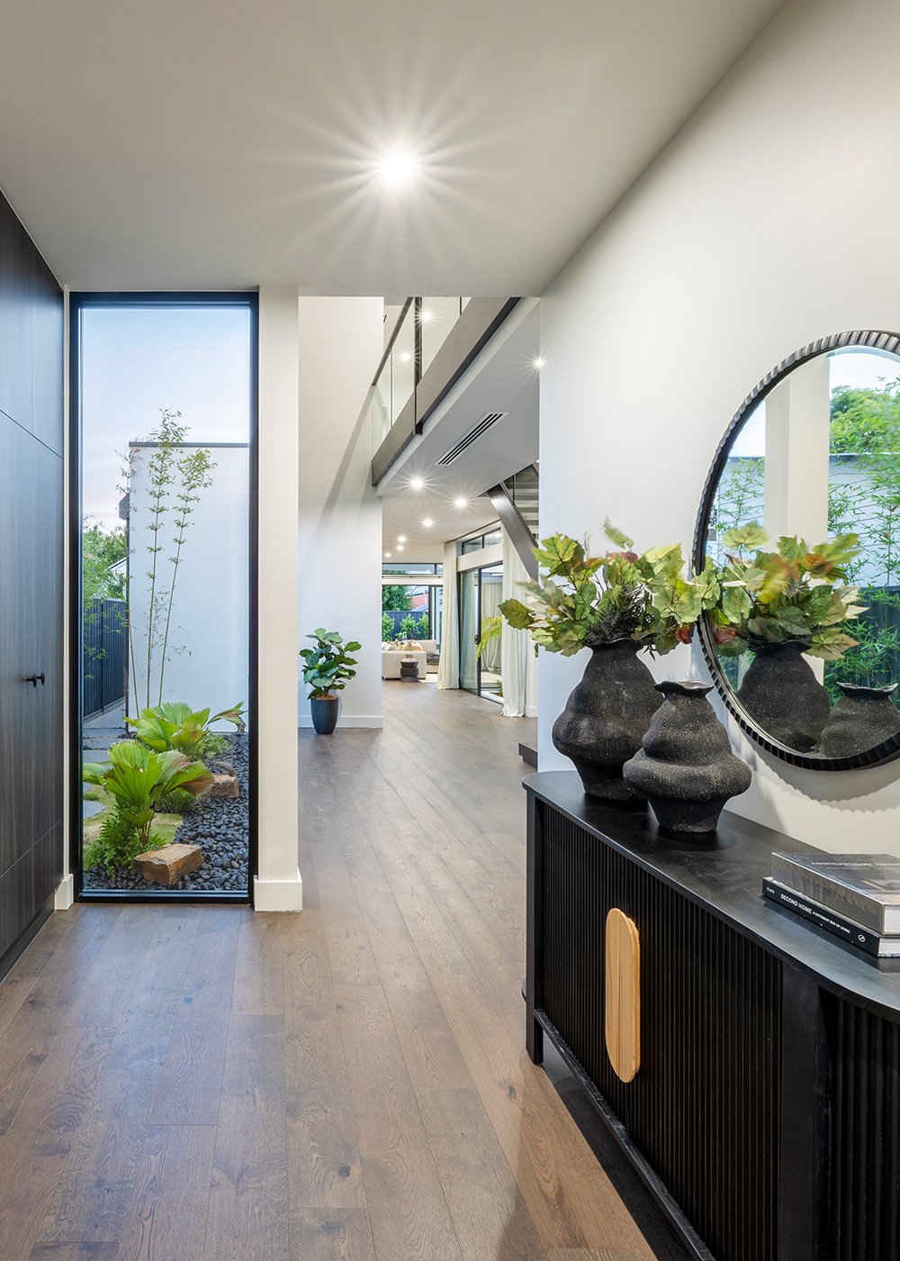 Entrance Hallway with dark timber hall table and decorative vases opening up to a large room with staircase